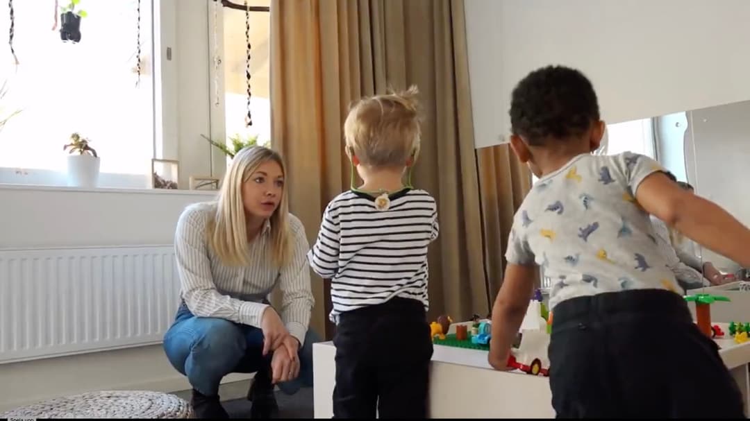 Kvinna sitter på huk , två barn leker