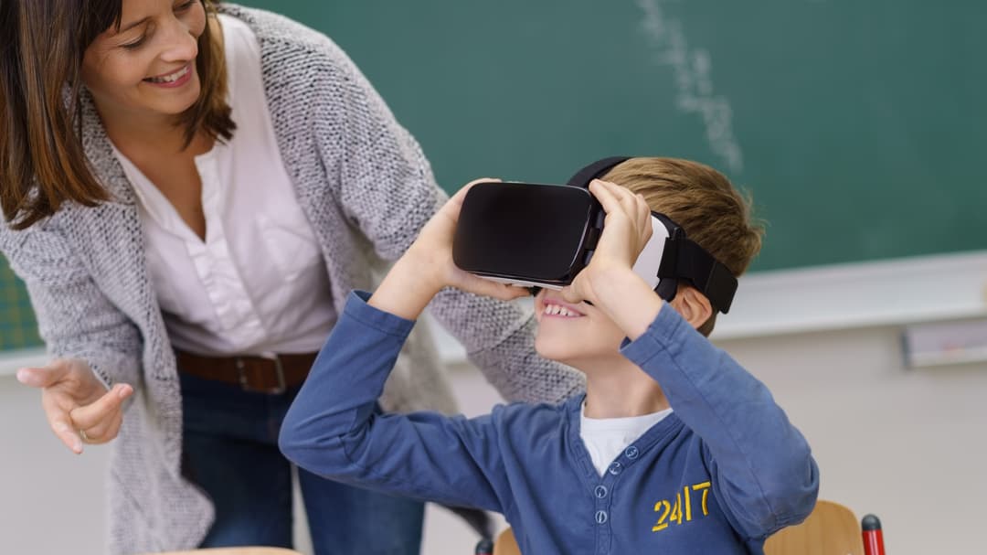18949051-smiling-teacher-watching-a-boy-in-vr-goggles.jpg