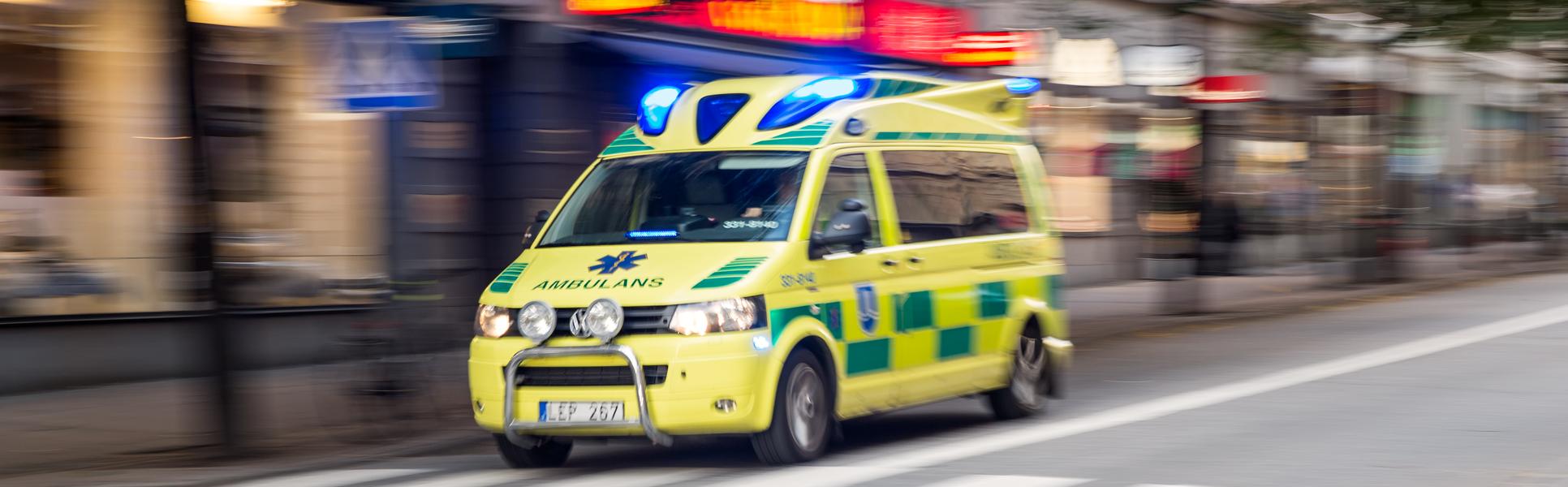 Stor ambulans under utryckning i stadsmiljö.
