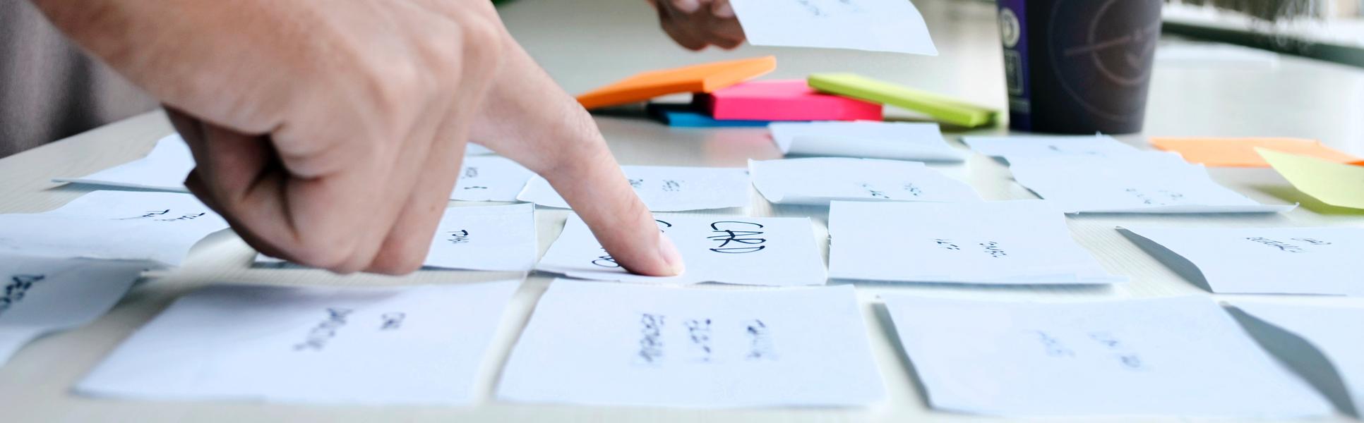Två händer som ordnar post it lappar på ett bord