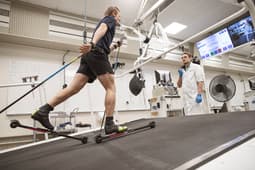 Alfred Buskqvist åker rullskidor på rullband med testutrustning som mäter syreupptagning, övervakas av testledare Hampus Lindblom.