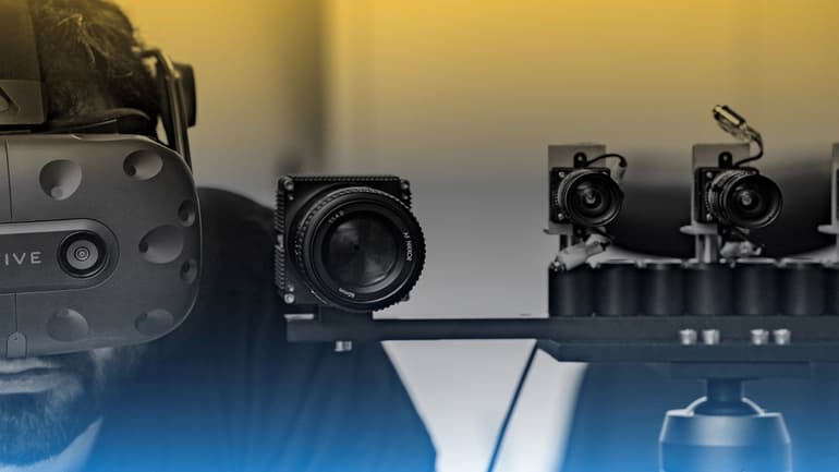 En man har vr-headset på sig och står bredvid en uppsättning med små kameror.