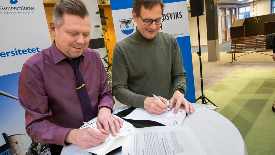 Rektor och kommunchefen i Örnsköldsviks kommun signerar varsitt dokument 