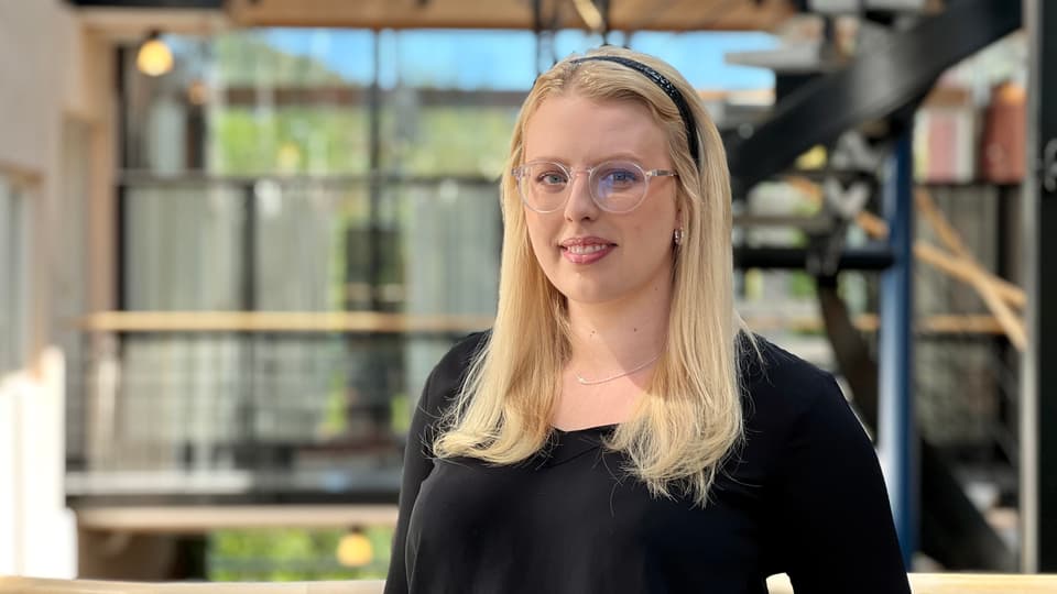 A blonde woman with glasses and a black sweater