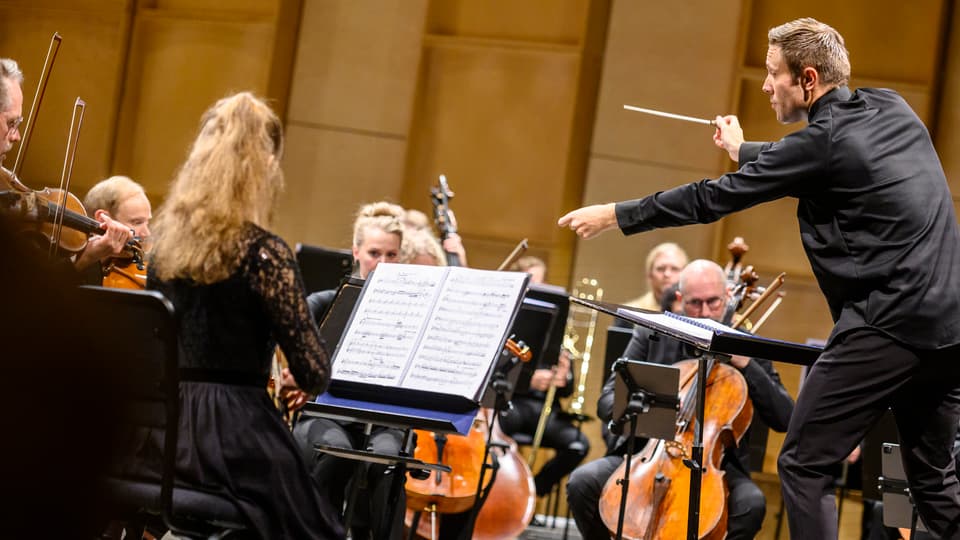 man i skjorta dirigerar orkester
