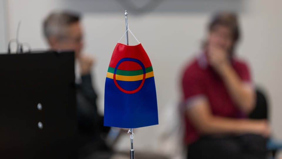 Den samiska flaggan i förgrunden och två människor utan fokus i bakgrunden