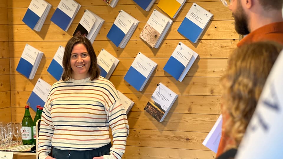 Karin Larsson-Hult står framför en vägg av uppspikade avhandlingar