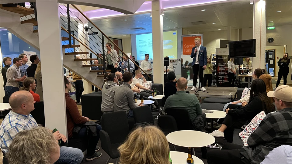 Ett rum fyllt med människor och en man med mikrofon på en scen