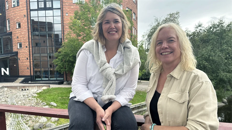 två leede kvinnor framför ett staket