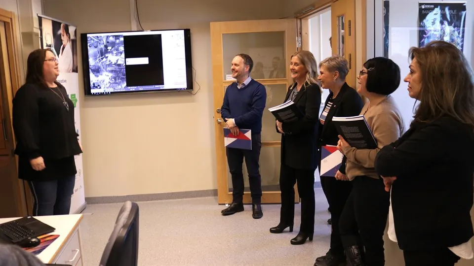 five persons standing and watching screens