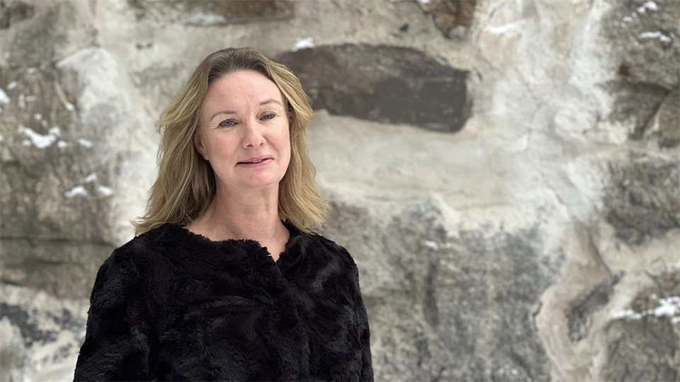 Kvinna står framför en stenmur.