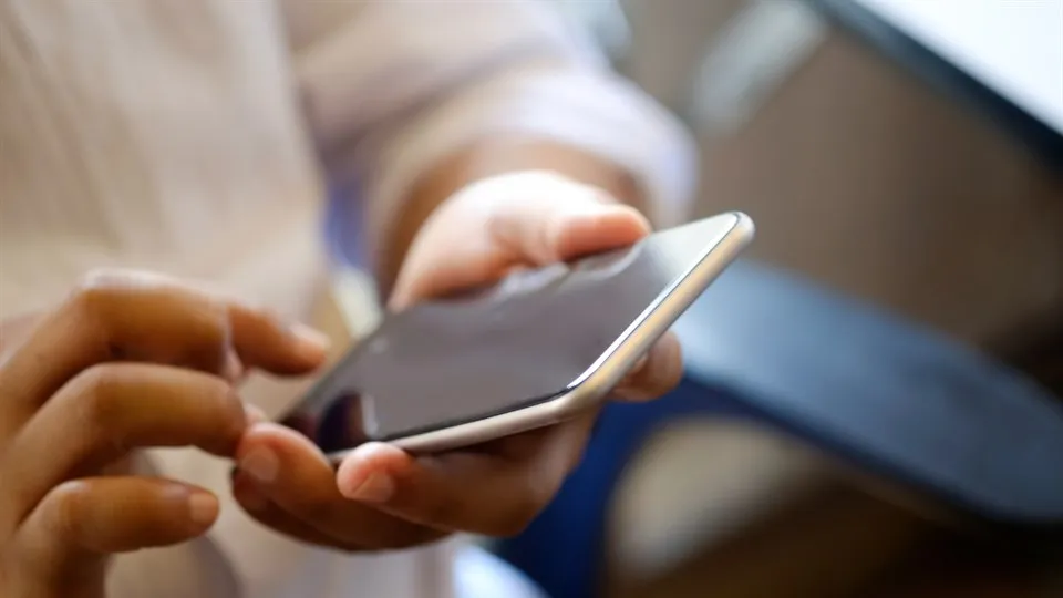 Närbild man håller mobiltelefon