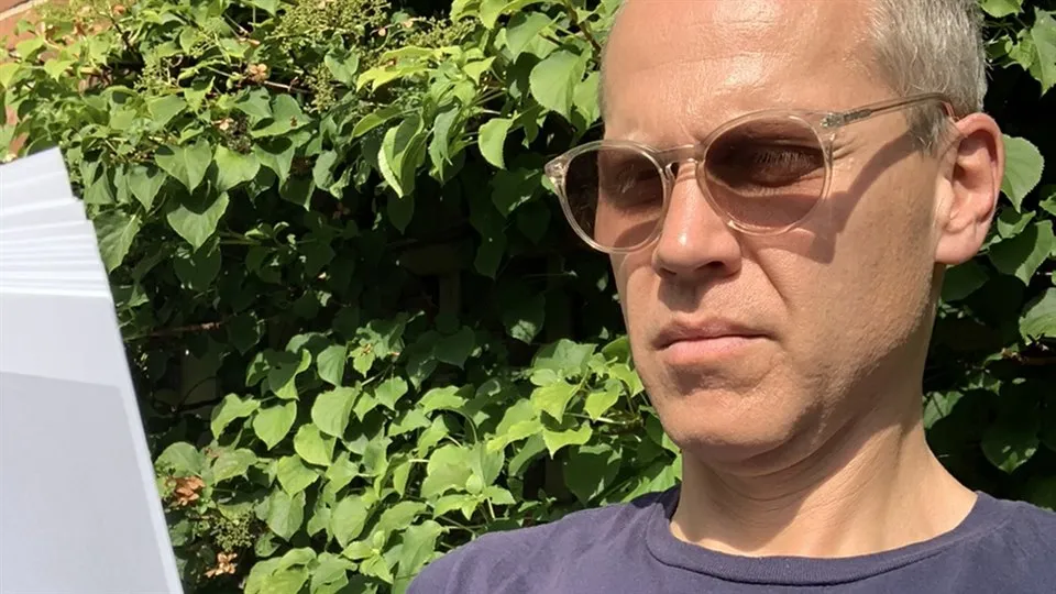 Per Becker sitter i solen och läser