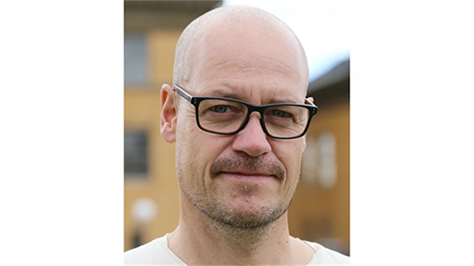 En man i svarta glasögon och rakat huvud.