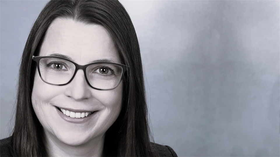 A woman with brown hair and glasses smiles