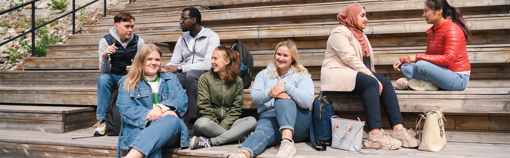 Seven students sitting on a staircase.