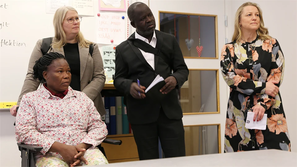 Four people listen interested in a classroom.