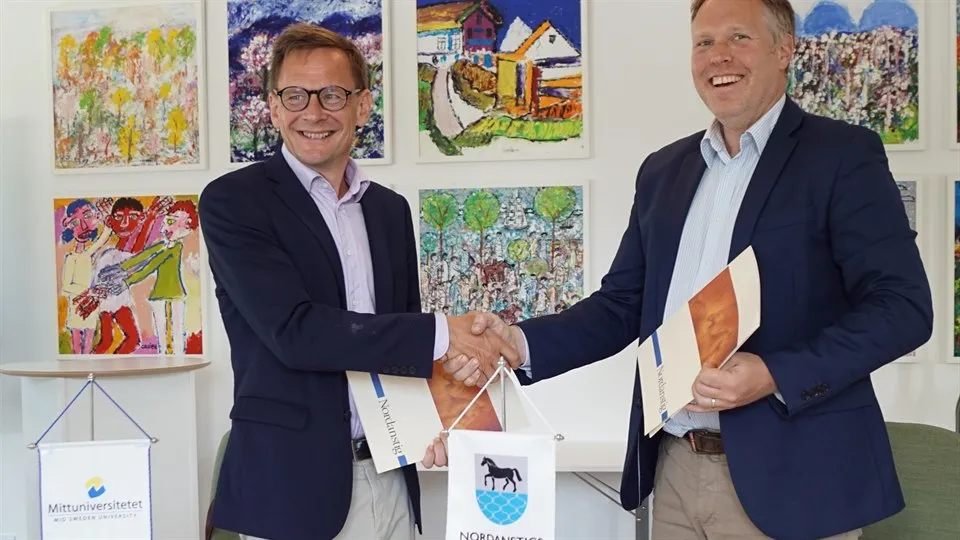 Två män skakar hand och ler