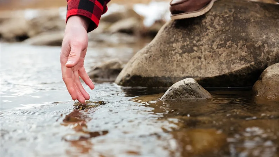 Vattendrag hand testar vatten