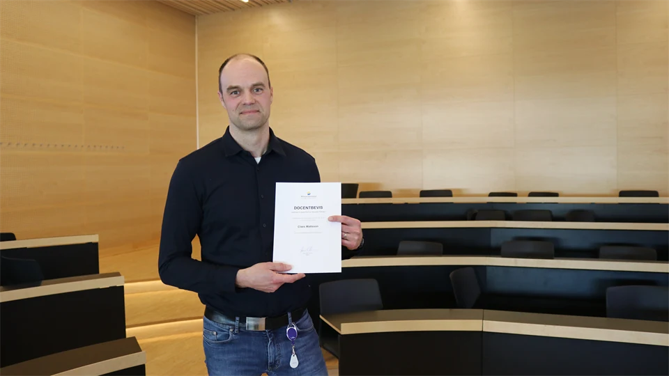 A person stands and presents an associate professor’s certificate.