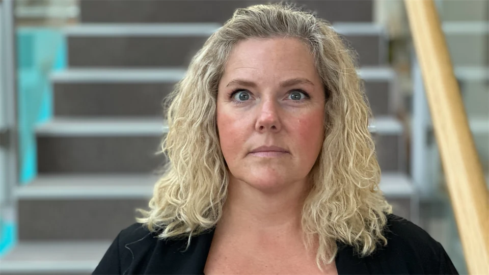 En kvinna med blont hår framför en trappa