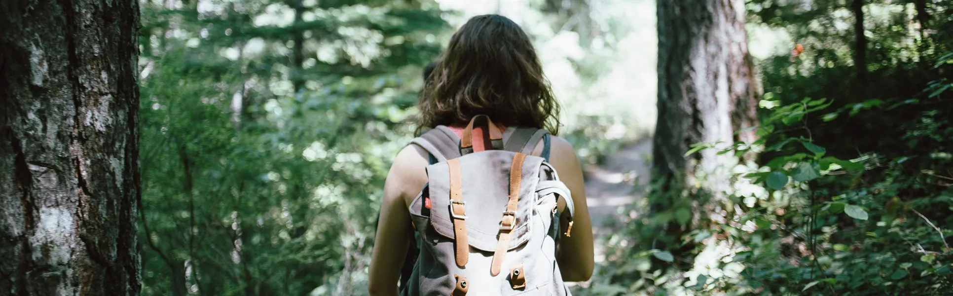 Kvinna med ryggsäck går genom skog