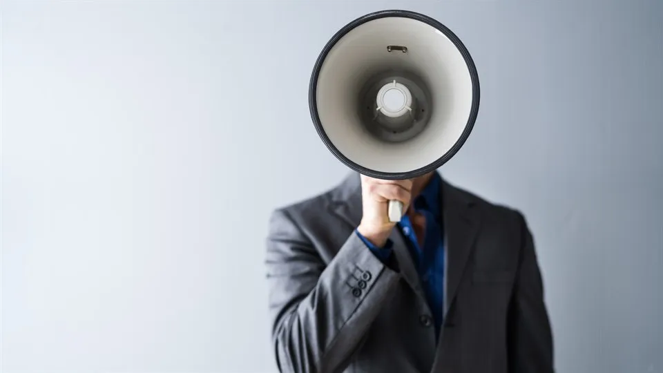 En man i kostym står med megafon framför ansiktet