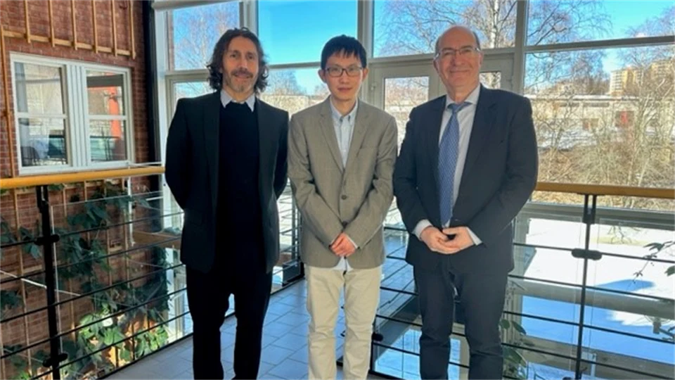 Three well-dressed people are standing in front of a large window