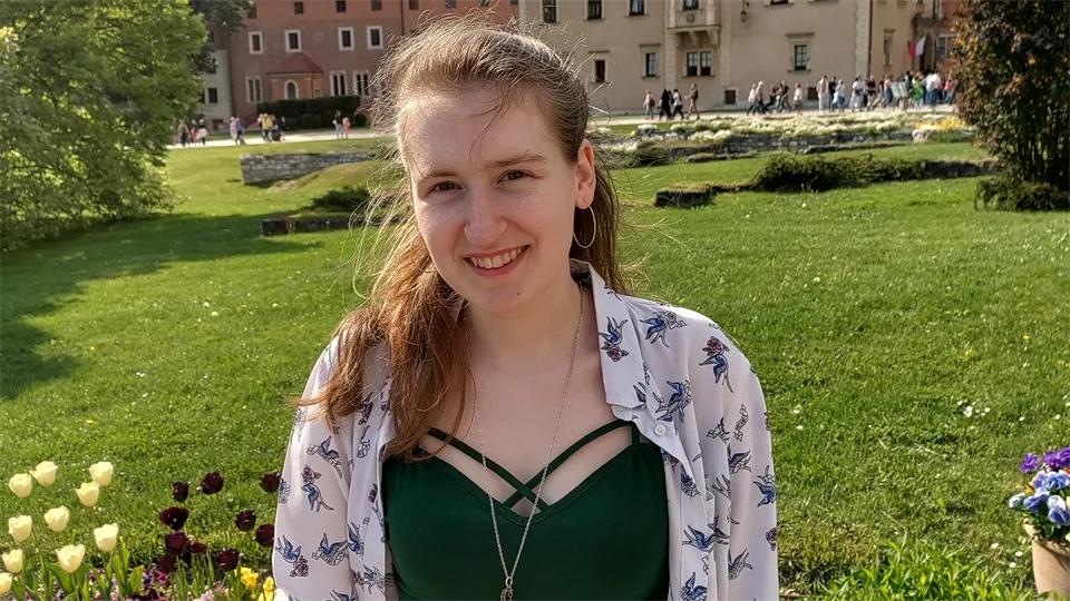 Kvinna med grön tröja framför en blomsterrabatt