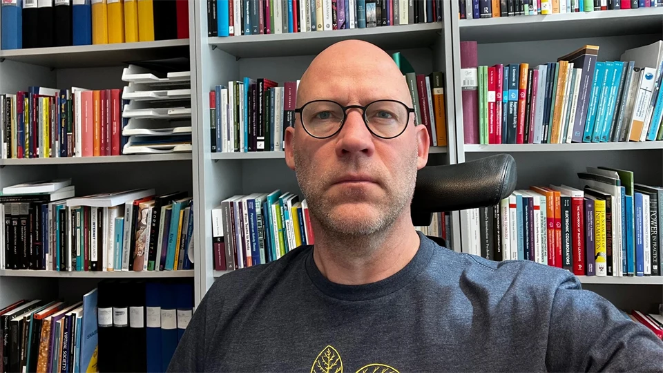 Jimmy Jaldemark framför en bokhylla med böcker