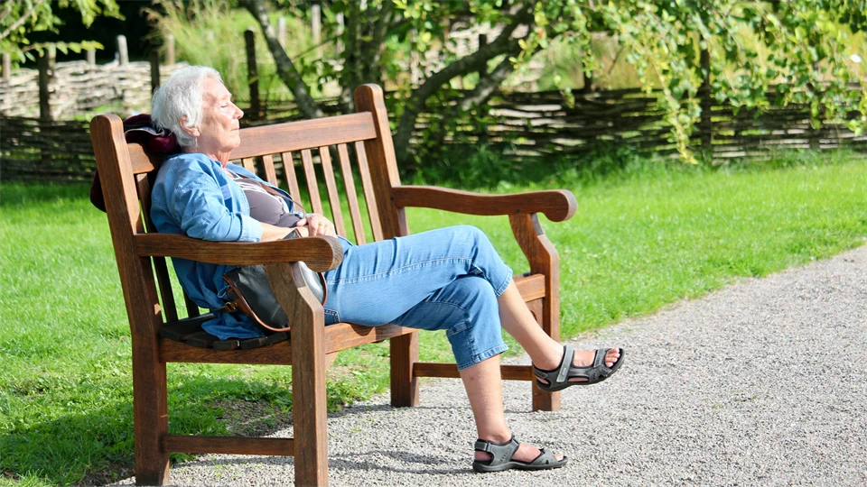 Äldre dam på parkbänk