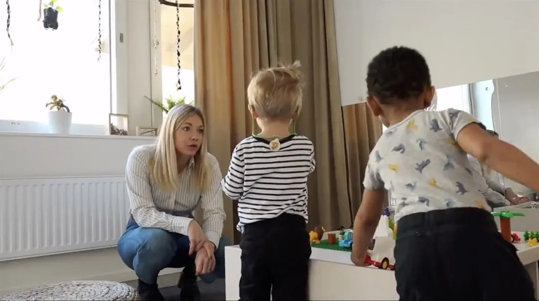 Kvinna sitter på huk , två barn leker