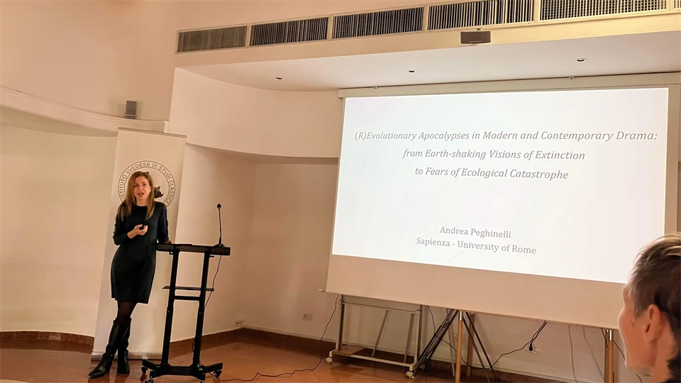 En kvinna klädd i svart står vid ett bord och föreläser