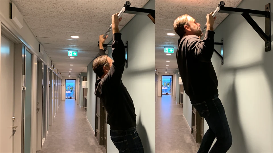 Man som häver sig upp på en chinstång i en korridor.