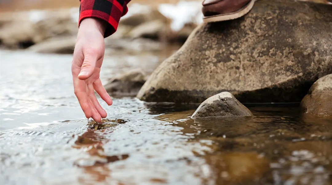 Vattendrag hand testar vatten