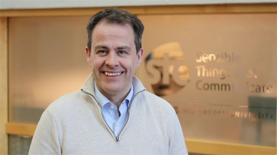 A man with dark hair and white sweater