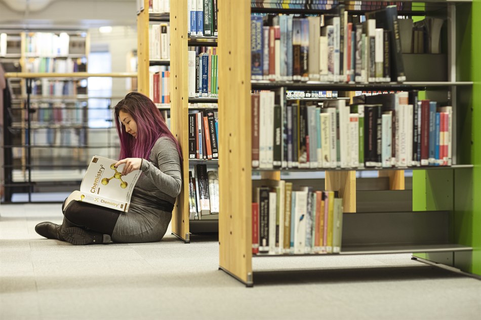 Läser bok sittande på golvet