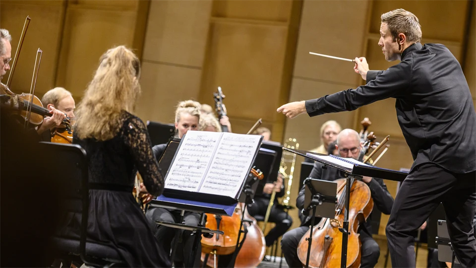 man i skjorta dirigerar orkester