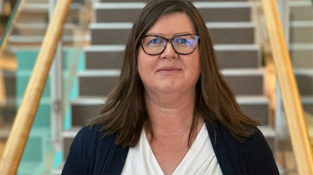 En kvinna med brunt hår står framför en trappa