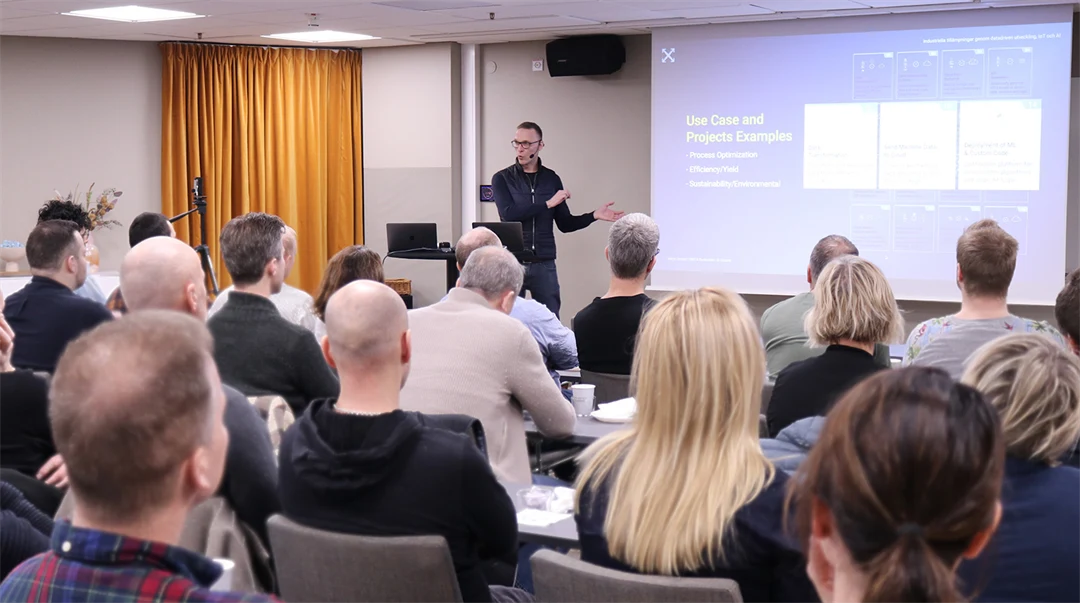 En man står framför en publik och talar. 