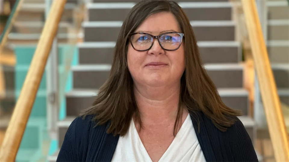 En kvinna med brunt hår står framför en trappa