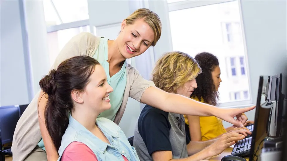 Computer teacher helping female students in her class