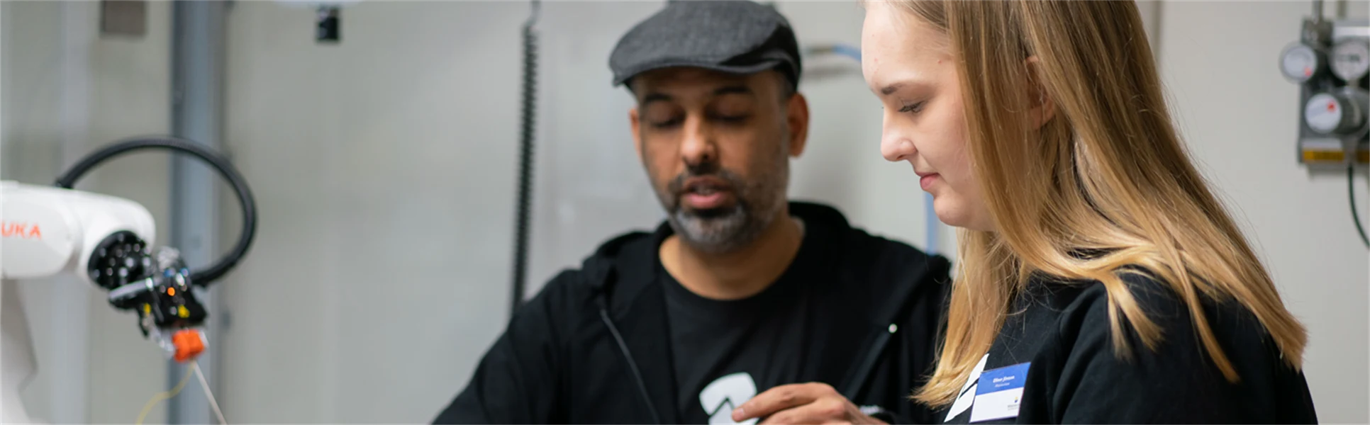 Man och kvinna som justerar en robotarm.