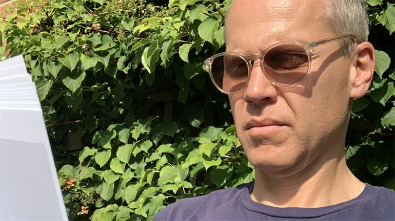 Per Becker sitter i solen och läser