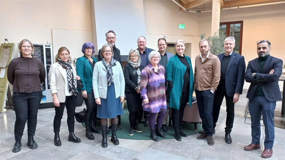 Thirteen people are lined up for a group photo.