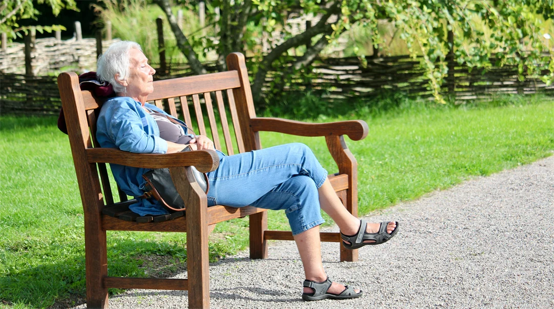 Äldre dam på parkbänk