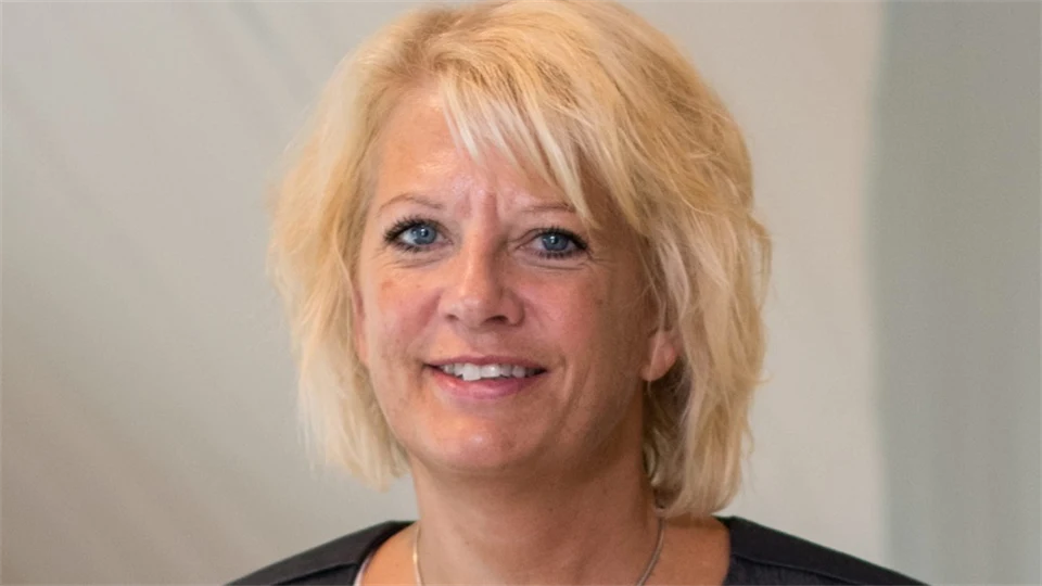 Ljushårig kvinna som tittar in i kameran och ler