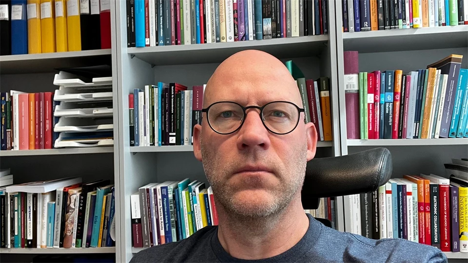 Jimmy Jaldemark framför en bokhylla med böcker