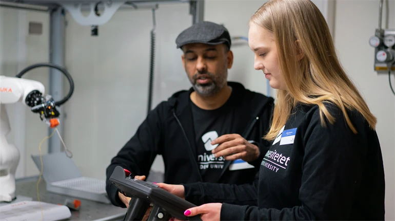 Man och kvinna som justerar en robotarm.