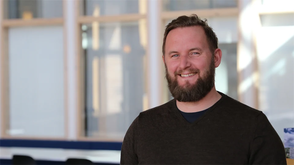 Porträtt av en leende man med skägg.